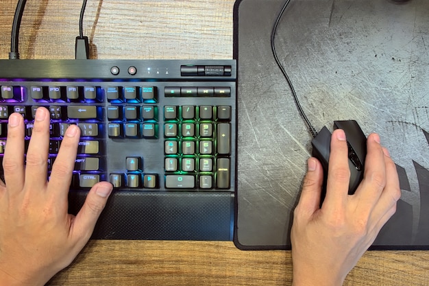A close-up shot of a player's hands on a keyboard during a League of Legends match, with their face blurred and a rainbow flag pin subtly visible on their shirt, symbolizing the player's identity and dedication within the esports environment.